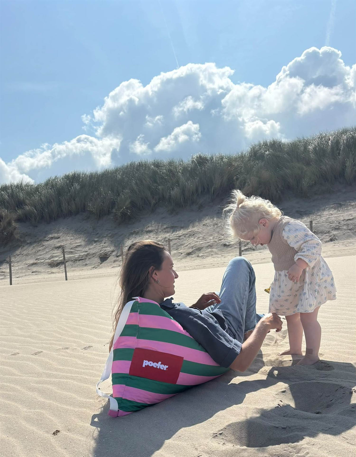 Moeder en kind spelen bij de Poefer op het strand